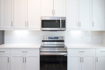 a white kitchen with white cabinets and a stove and microwave